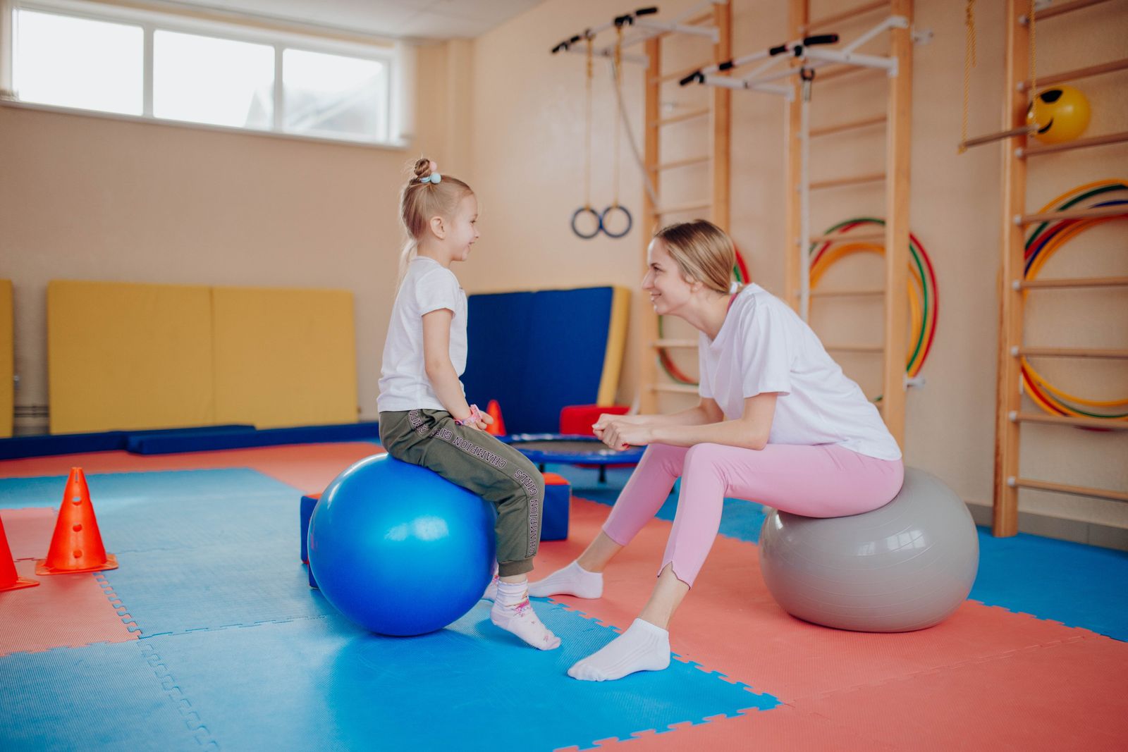 A young girl balancing on a therapy ball with her physiotherapist